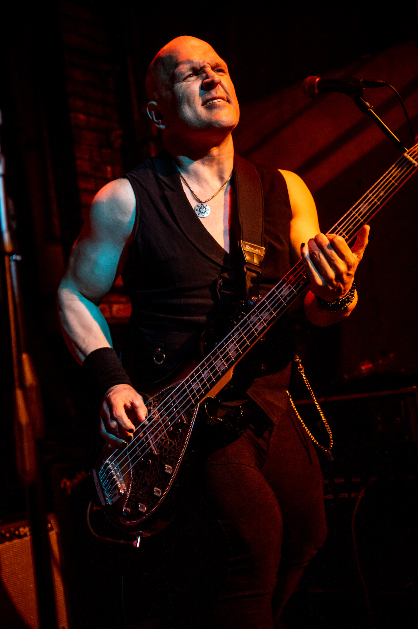 Danny Knapp playing electric bass on stage, eyes closed, in warm stage light.
